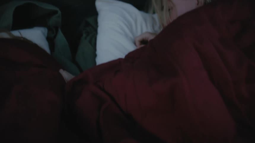 A woman pulls a sleeping bag back to check on her son next to her in a tent