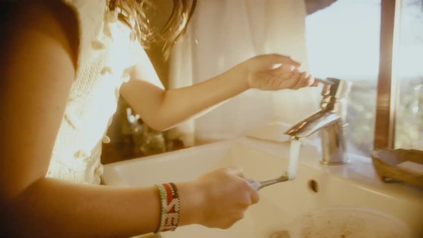 A girl brushing her teeth at a bathroom sink