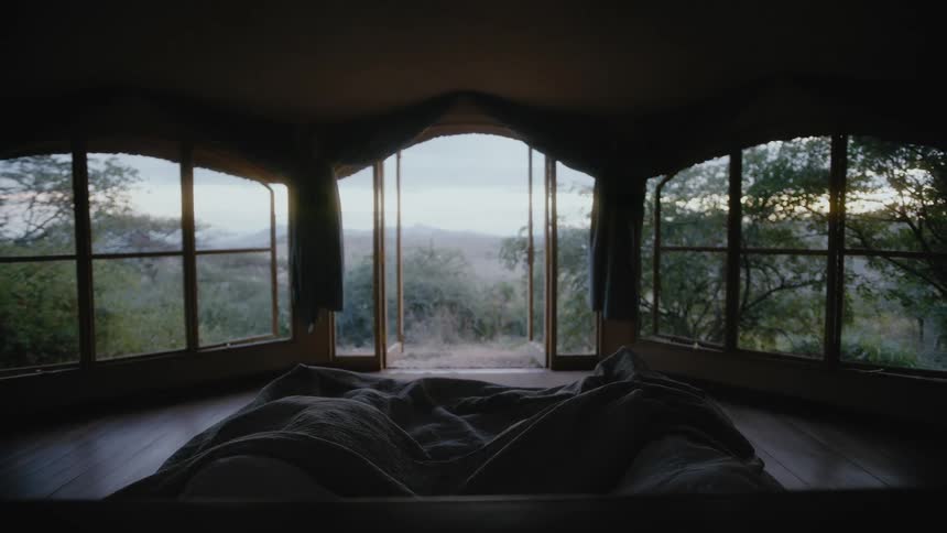 Two people sleeping in a bedroom open to a savanna