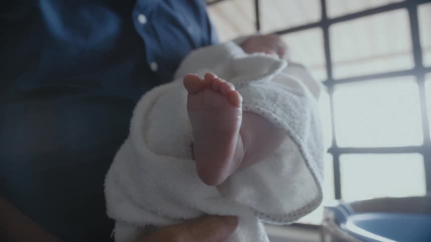 A man is holding a baby in a towel