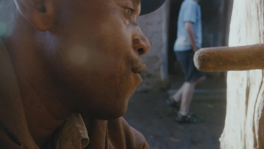 A man is sitting outdoors wearing a hat