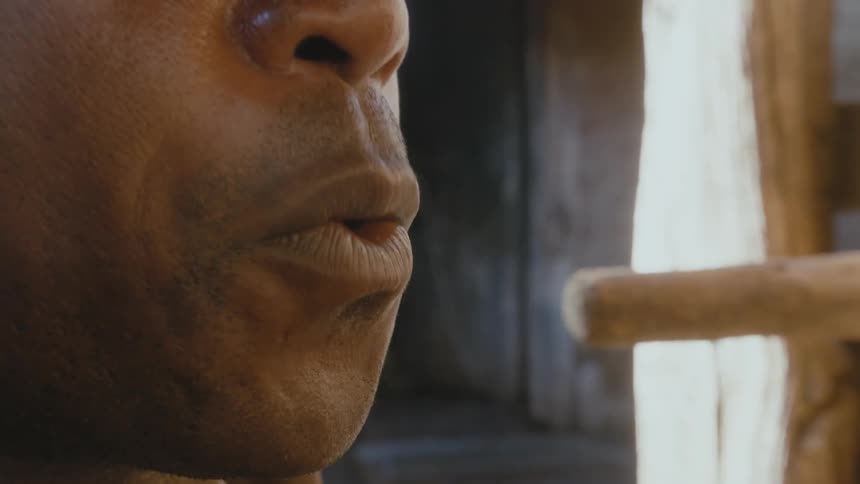 A man blows on the end of a stick as smoke billows from it