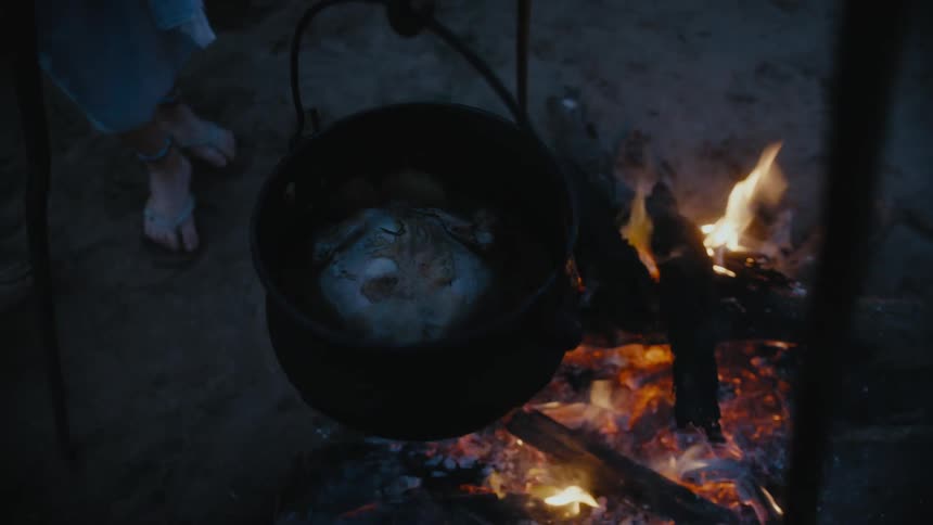 The campfire is heating the hanging pot