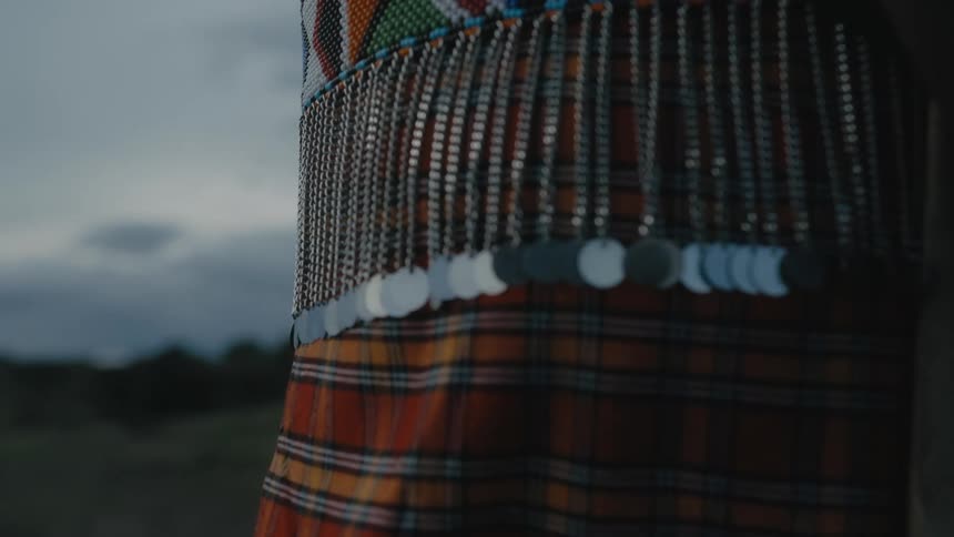 Metal waist chain link hanging from the belt of a woman standing outdoors at evening