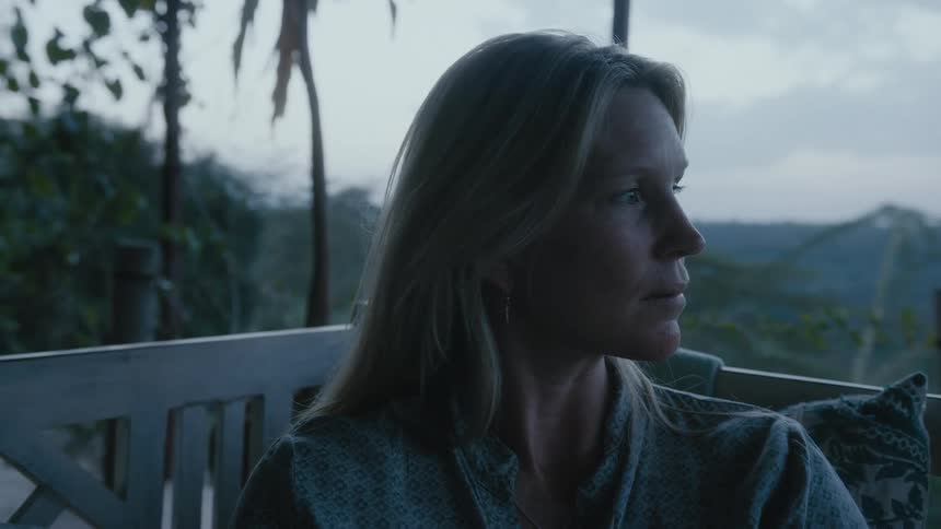 Blonde woman sitting at the balcony of her house looking at the landscape view outside