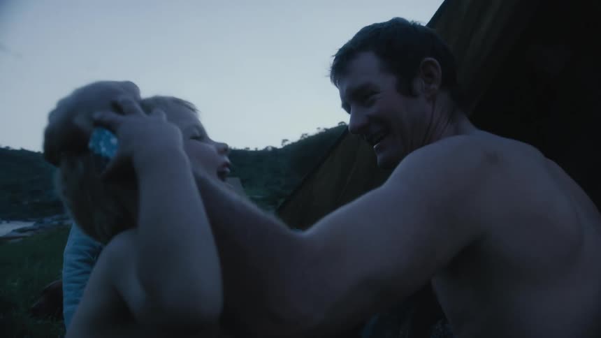 Boy walks across field to tent passing his sister and being greeted with a hug by his father