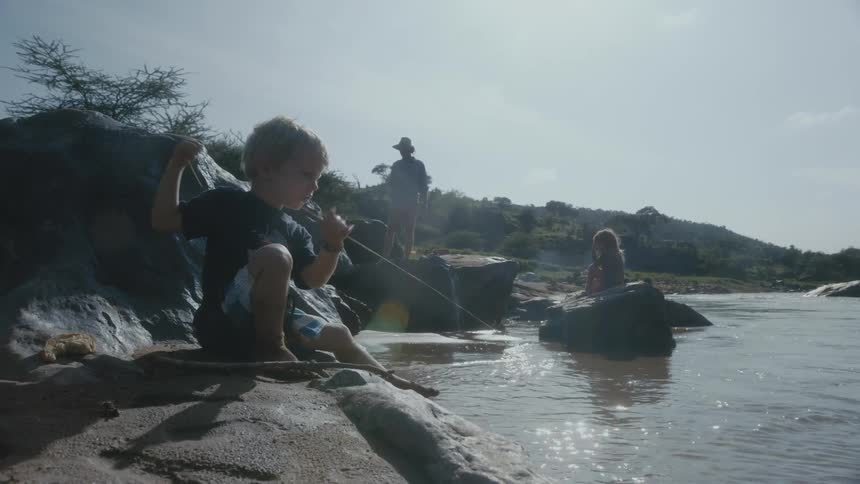 Two kids are fishing on a river outdoors