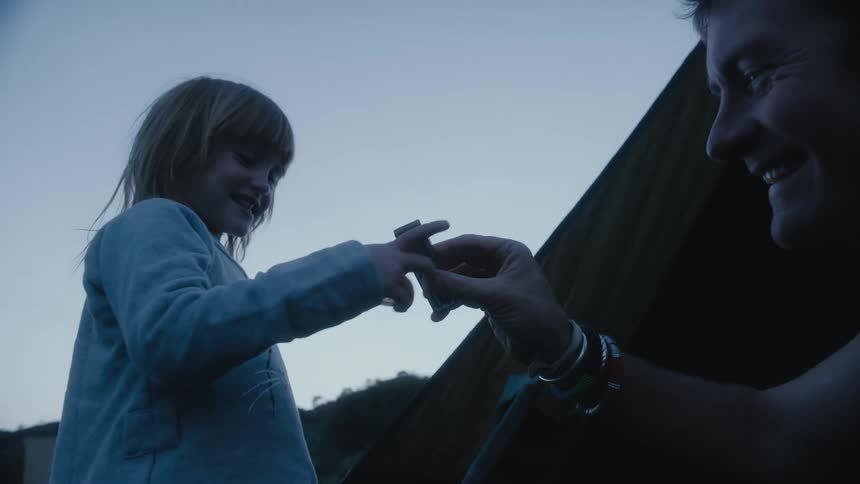 Father and daughter are camping outdoors together