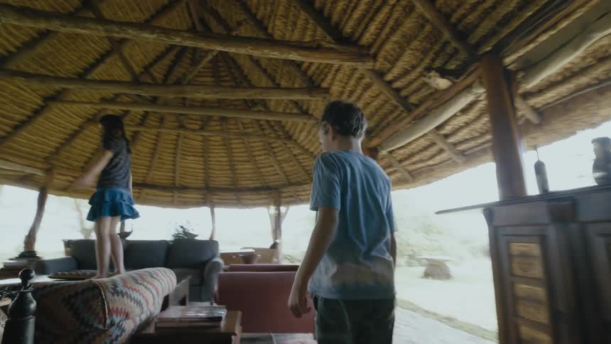 Two children jump around the furniture under the canopy