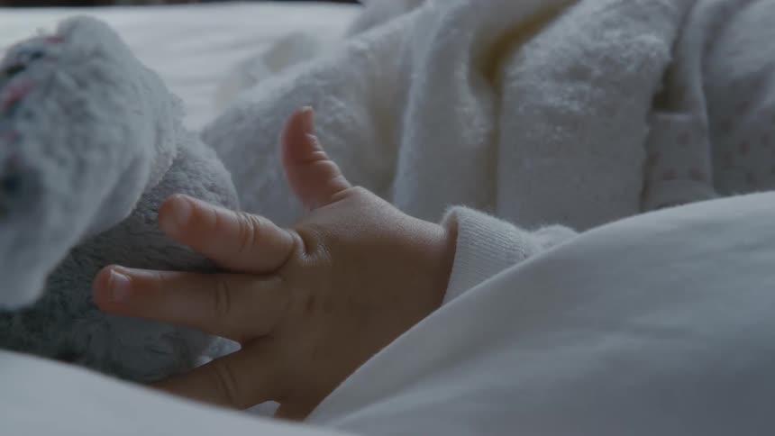 Baby grabs onto the ear of a stuffed toy and pulls it towards himself