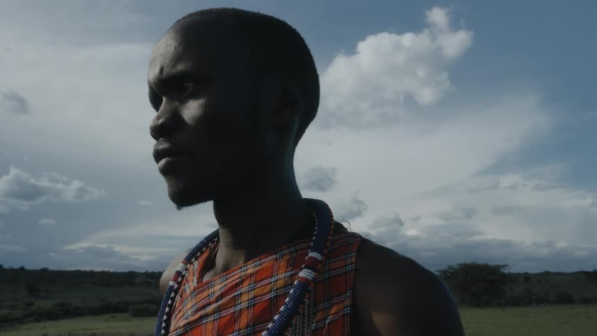 African male shepherd with traditional outfit takes care of sheep and goat in the field