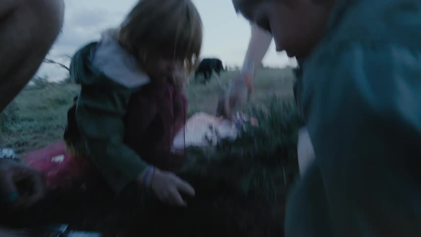 Two children are shown how to plant herbs in a field