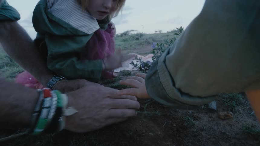 A young girl pats the ground as she helps her mom and dad plant