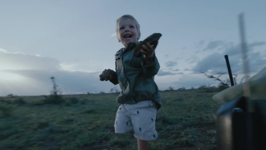 Boy helps his father collect rocks to plant a sapling in the plains at sunset