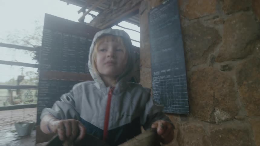 Little girl carries a bag out of a room and hands it to a man standing next to a horse in a stable