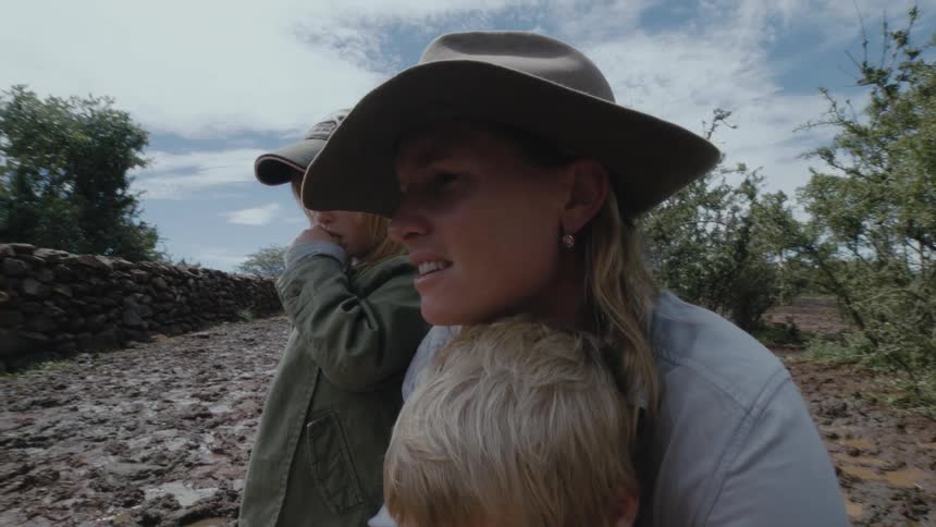 A woman and her children watch a newborn cow