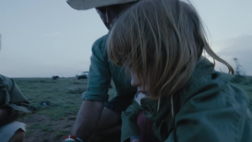 A mother is planting seeds outdoors with her children