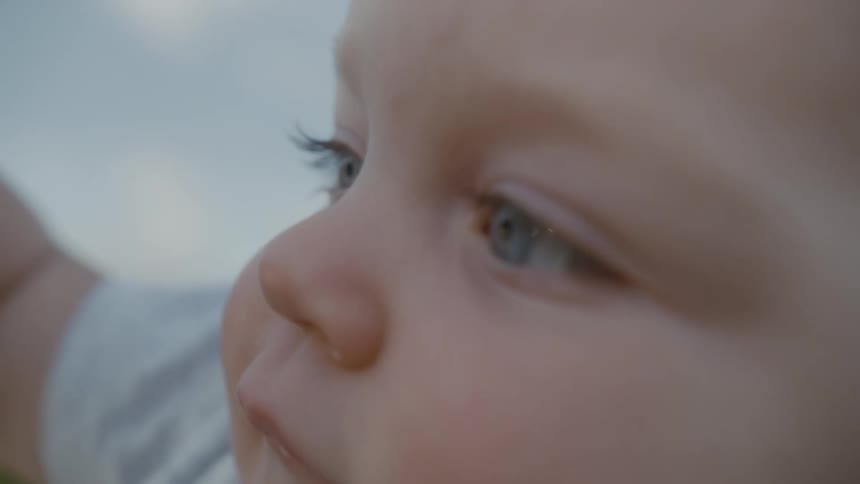 A blue eyed baby sitting outside