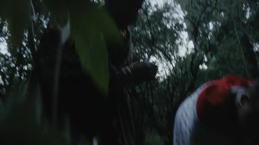 Man and woman dressed in costumes bend over and look on the ground in the forest