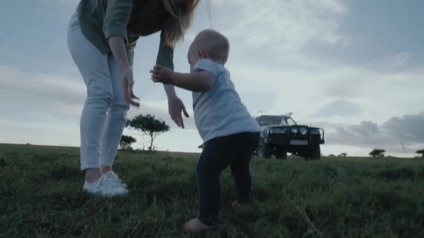Baby crawls through the grass toward mom then stands on her own