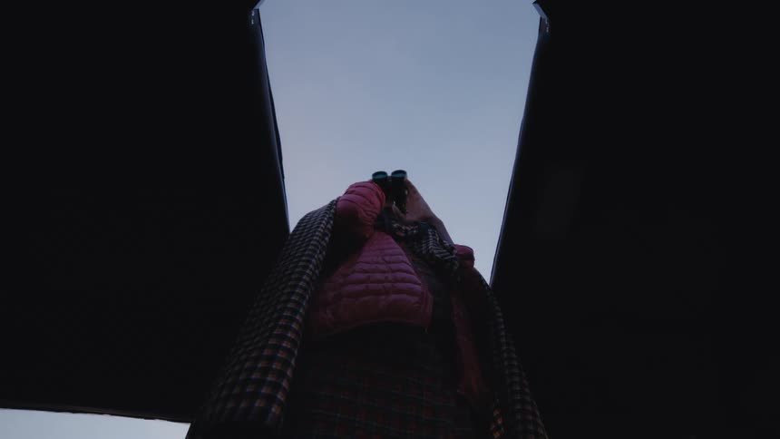 A person is standing and looking at binoculars