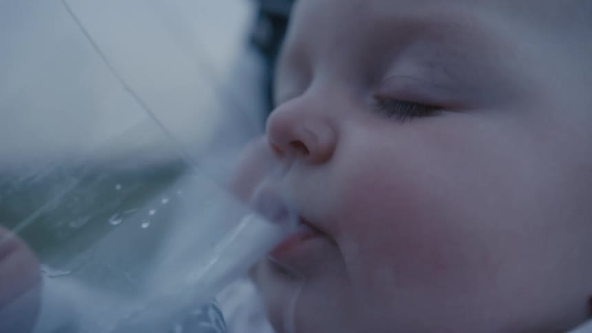 A baby drinking from a glass of water