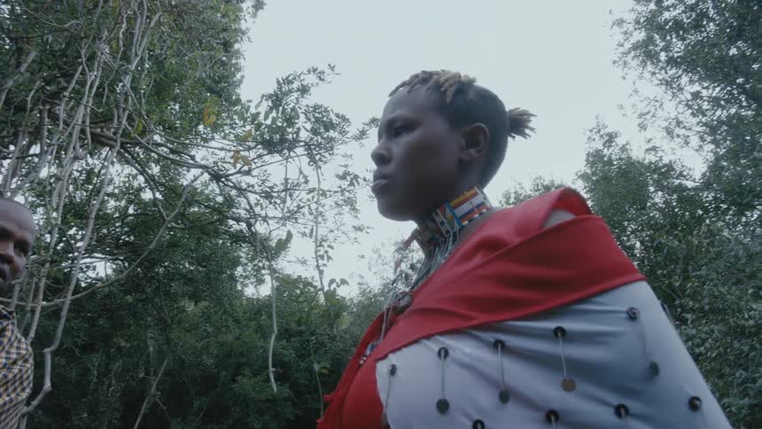 A woman nods while listening to a man talk about a tree in the forest