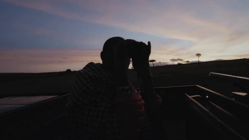 A man is using binoculars in the vehicle
