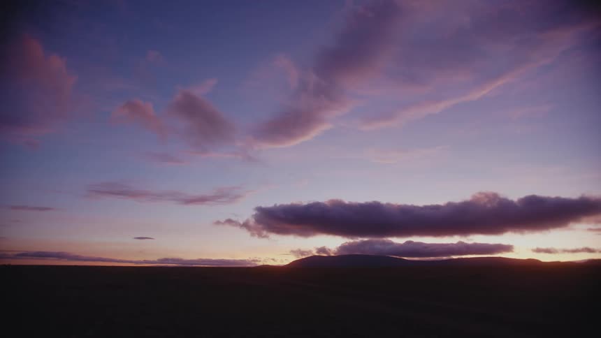 Purple clouds hang low in the sky over mountains