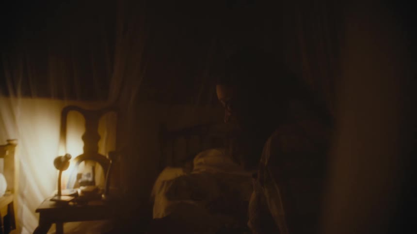 A woman is sitting on her bed