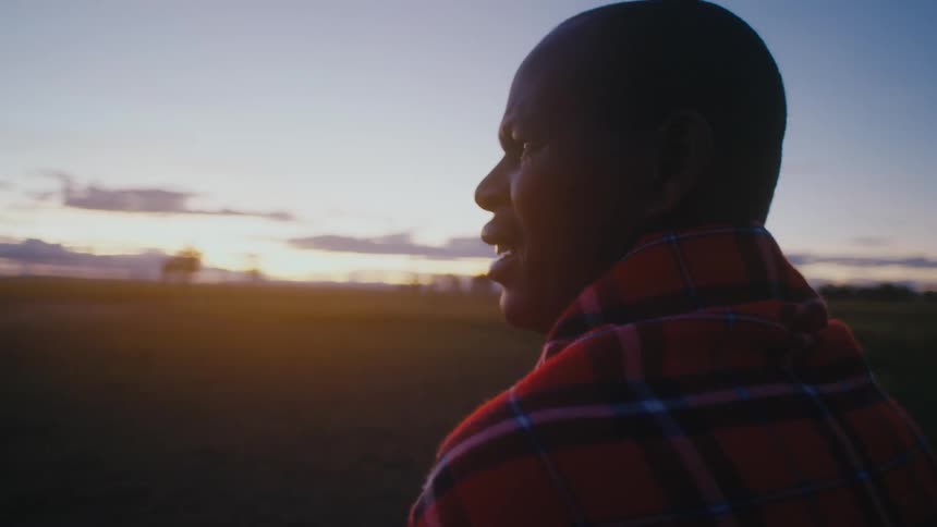 Black man standing alone at a grass field looking around confused
