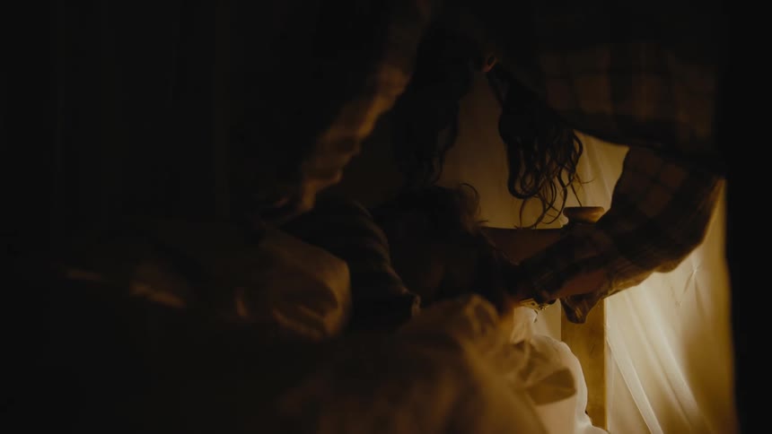A woman tucks in a child in bed