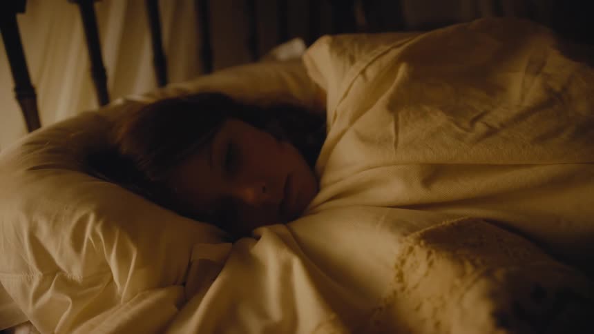 Woman deeply asleep in a cozy bed covered with thick white silk blankets