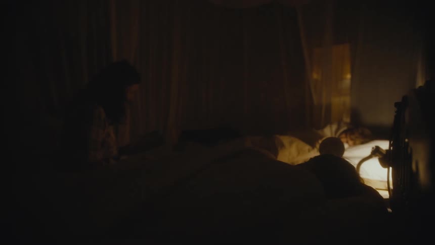 A woman sits near sleeping children