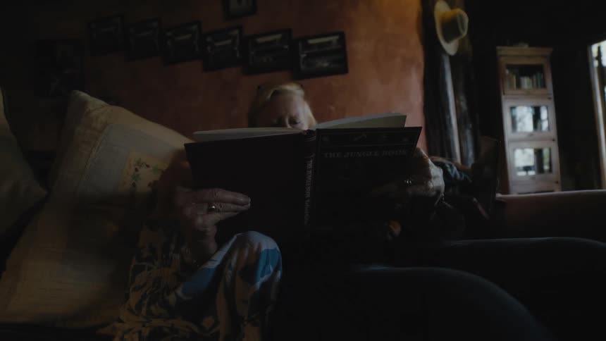 Grandmother sitting on the couch with her two granddaughters reading a book with them