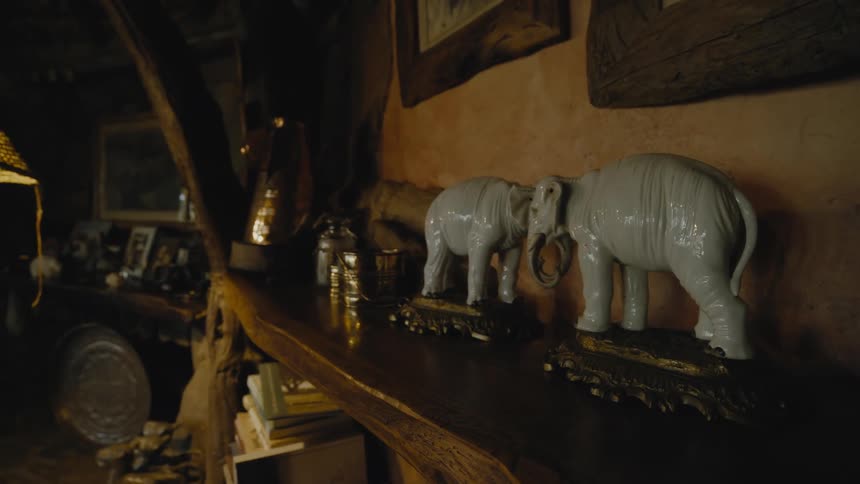 Two white elephant figurines butting heads on a mantle