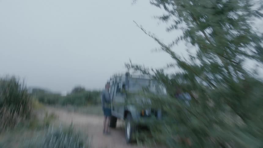 Boy and girl happily running towards a jeep parked in a dirt road