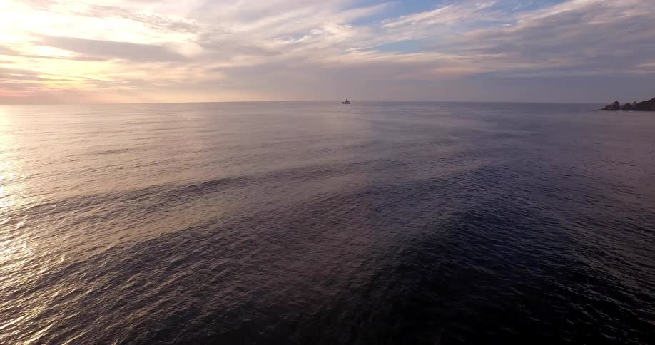 Aerial view moving over an ocean at sunset