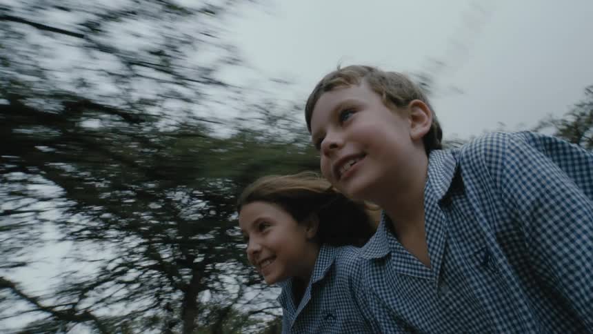 Happy boy and girl sitting on top of a car driving on a safari