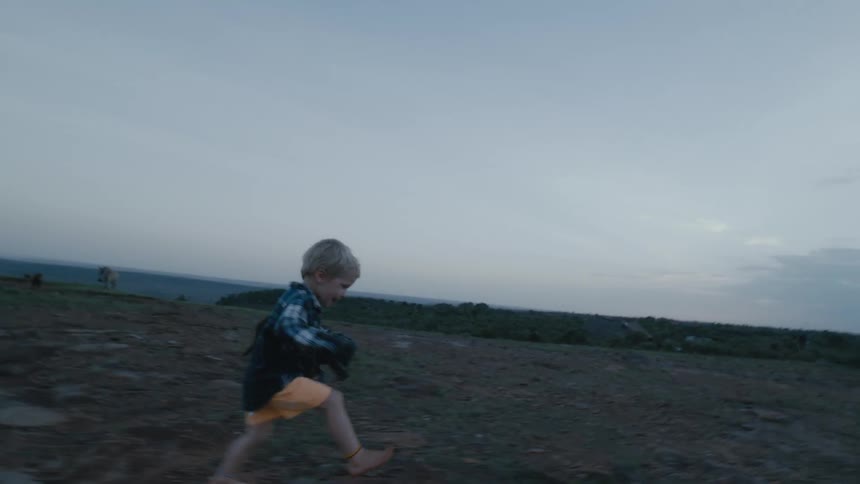 A man is walking outdoors with his son and pet dog