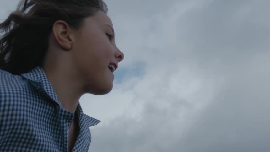 Smiling girl runs under a cloudy sky