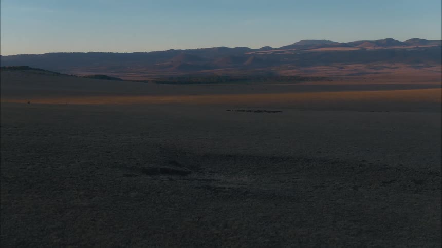 Aerial view of plains under the shadows of a mountain range at evening