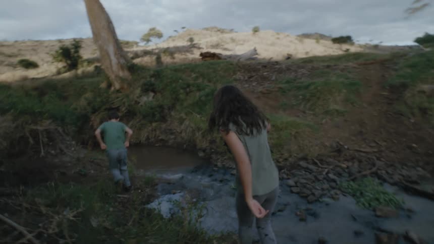Girl and boy hiking in nature beside a water stream