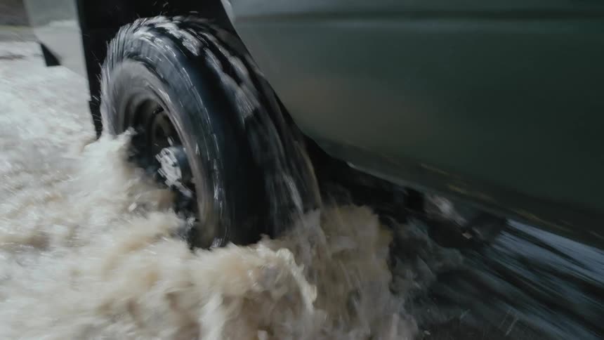 The tire splashes water as it passes