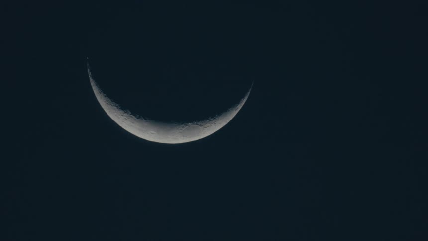 A crescent moon is in a dark night sky