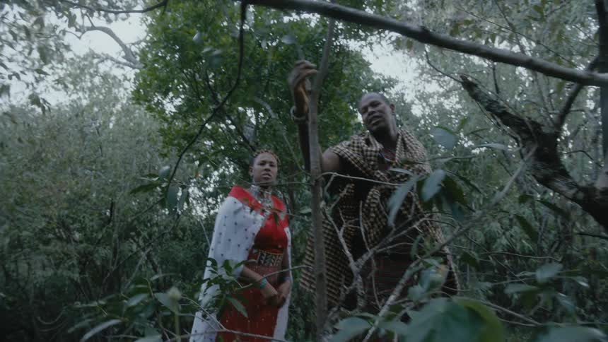 A man easily tears a branch off a small tree while a woman struggles to rip one off