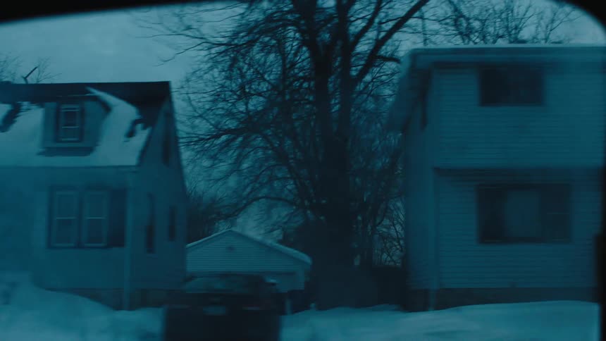 Looking out a car window passing neighborhood homes covered in snow on a gray day