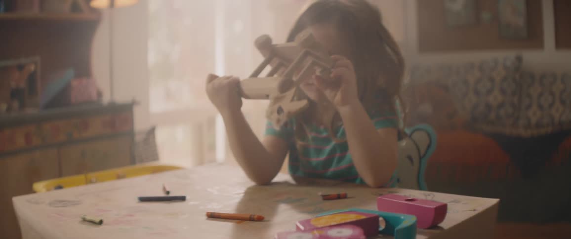 Bored girl sitting at desk plays with wooden rocking horse toy in her room