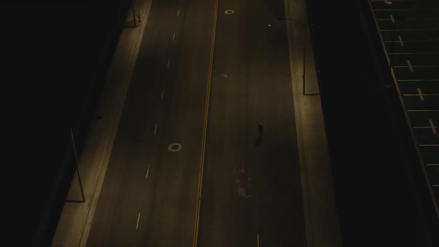 Cyclist bikes along empty road at night