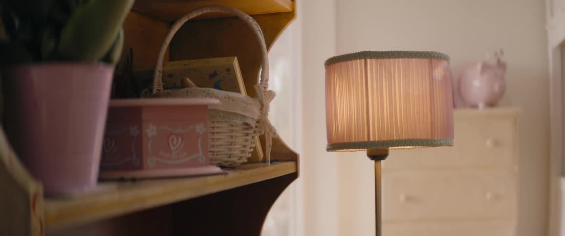 A vase of flowers and basket on shelf next to lamp in room